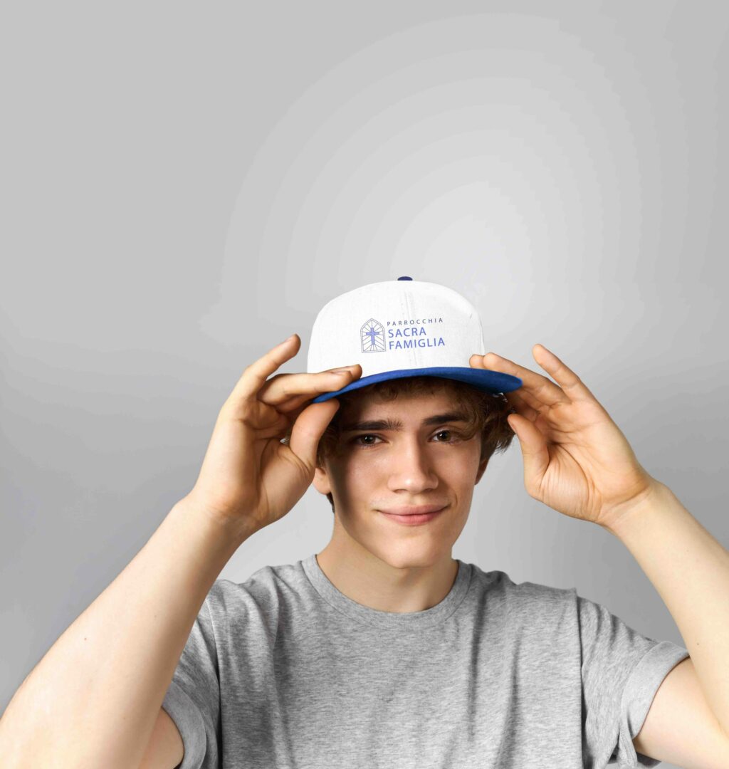 Ragazzo che indossa un cappellino bianco con visiera blu e una t-shirt grigia