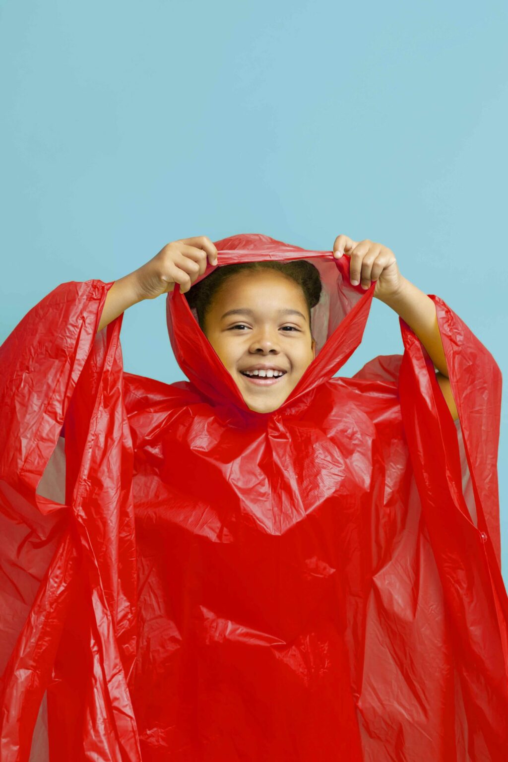 Bambina che indossa un poncho impermeabile con cappuccio rosso